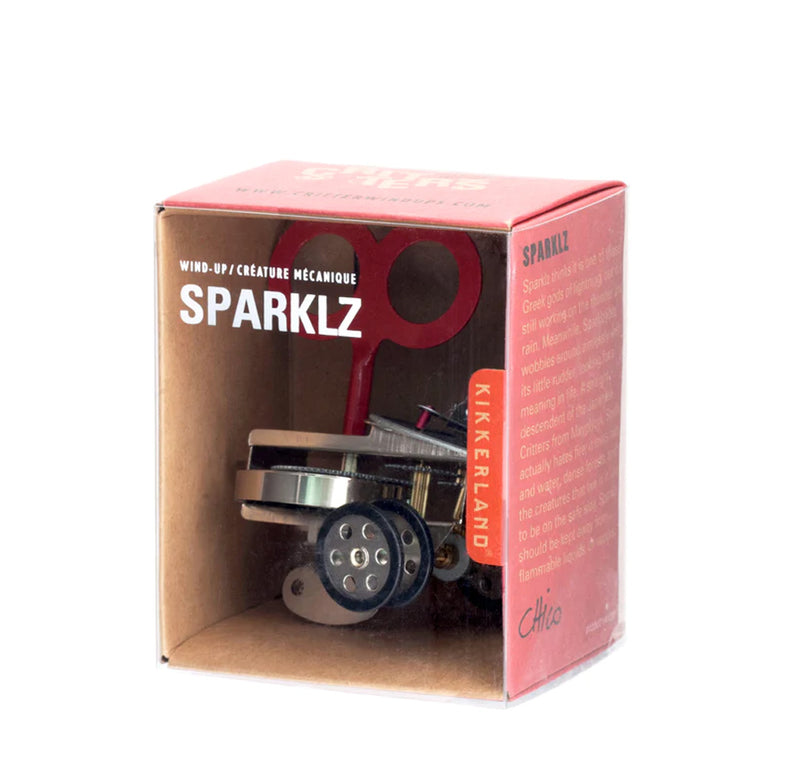 The Sparklz packaging: red colored cardboard with a clear plastic covering in the front showing the Sparklz inside. There is text on the side of the box describing the product. 