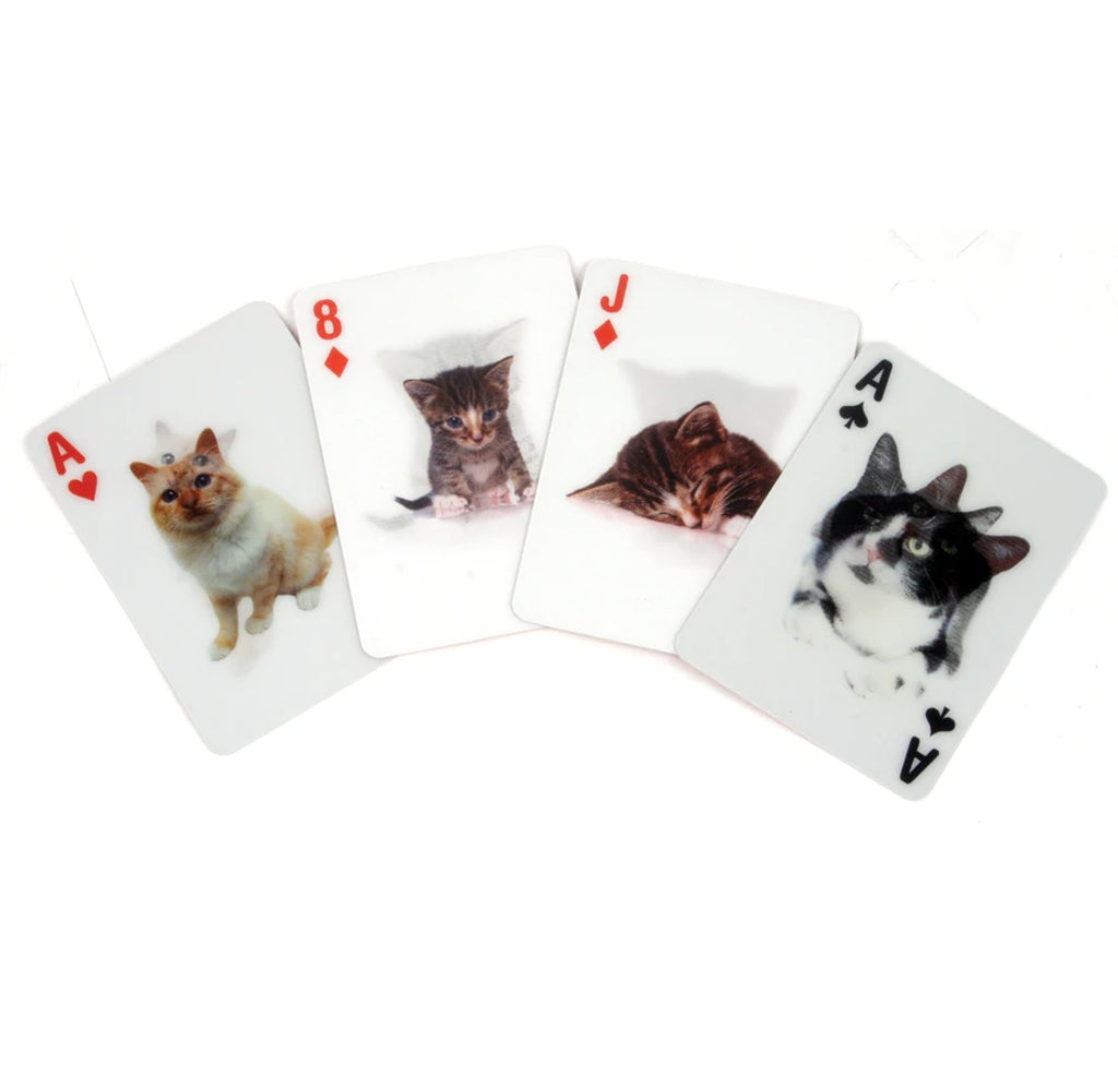 Ace of hearts playing card with beige cat, eight of diamonds playing card with a tabby kitten, jack of diamonds playing card with a sleeping tabby cat, and ace of clubs playing with black and white cat lie flat on the surface.