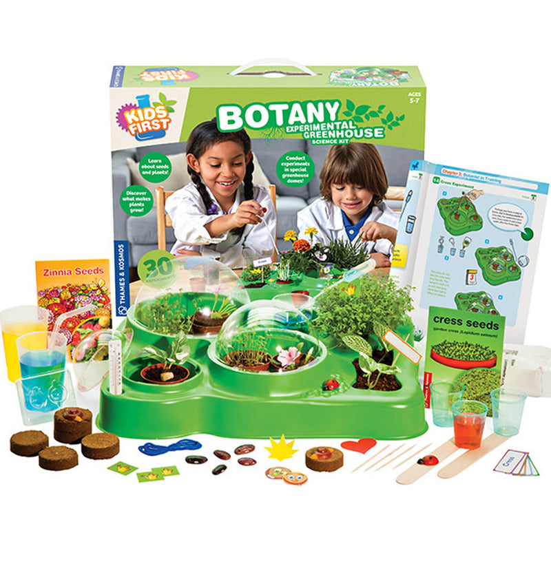 The product box is 14.6 x 11.5 x 3.1 inches in dimension. The photograph shows the kits set up with green plants and accessories, plant pots, soil pellets, a greenhouse with domes, and three seed packets.