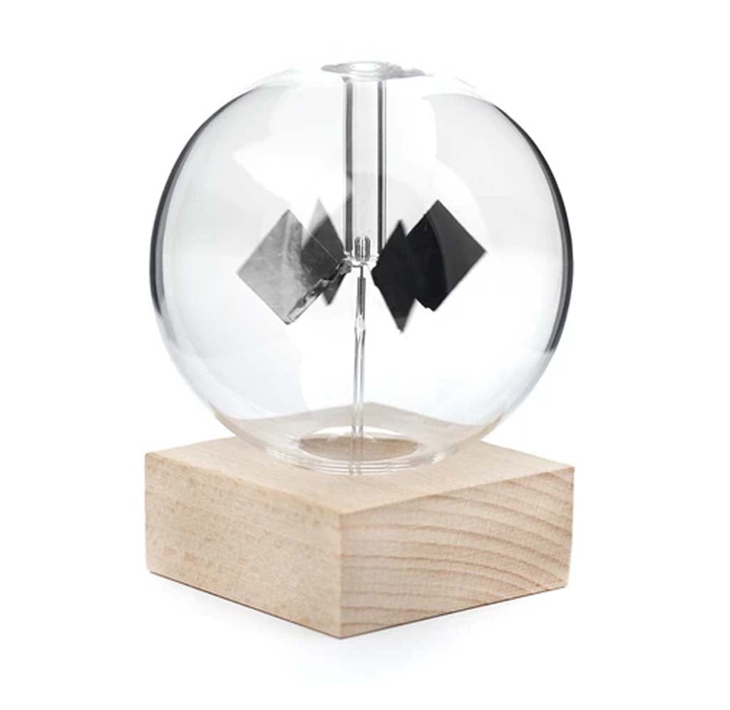 A clear circular globe sits atop a wooden base with four black triangular-shaped discs that rotate in the middle.