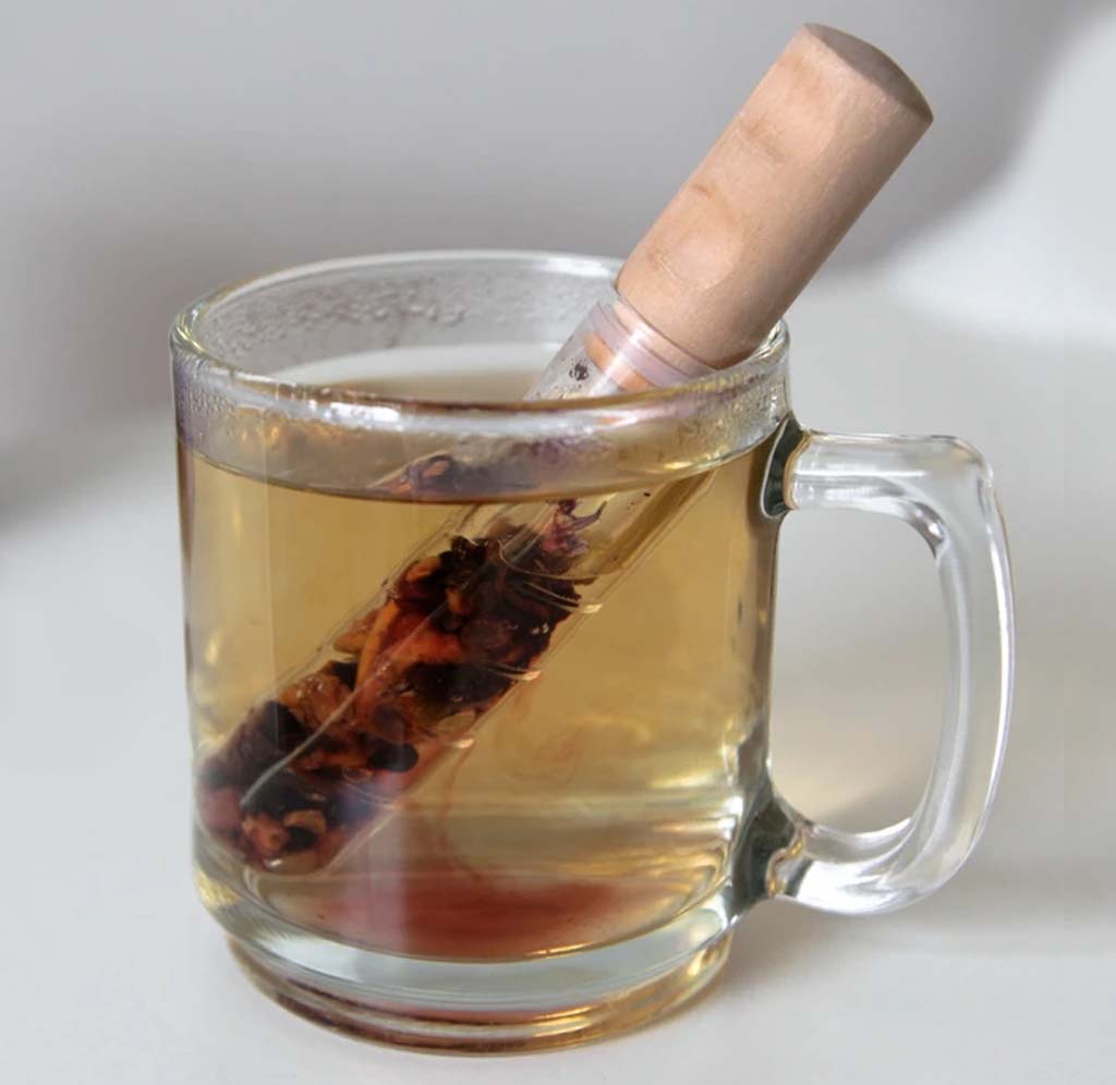 A small glass test tube with tea steeping in it sits inside a clear glass mug.