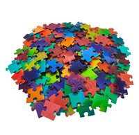 A pile of colorful jigsaw puzzle pieces in a rainbow of colors, photographed on a clean white background.