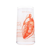 Clear drinking glass with red anatomical heart design on a white background