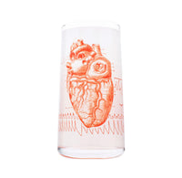 Clear drinking glass with red anatomical heart design on a white background