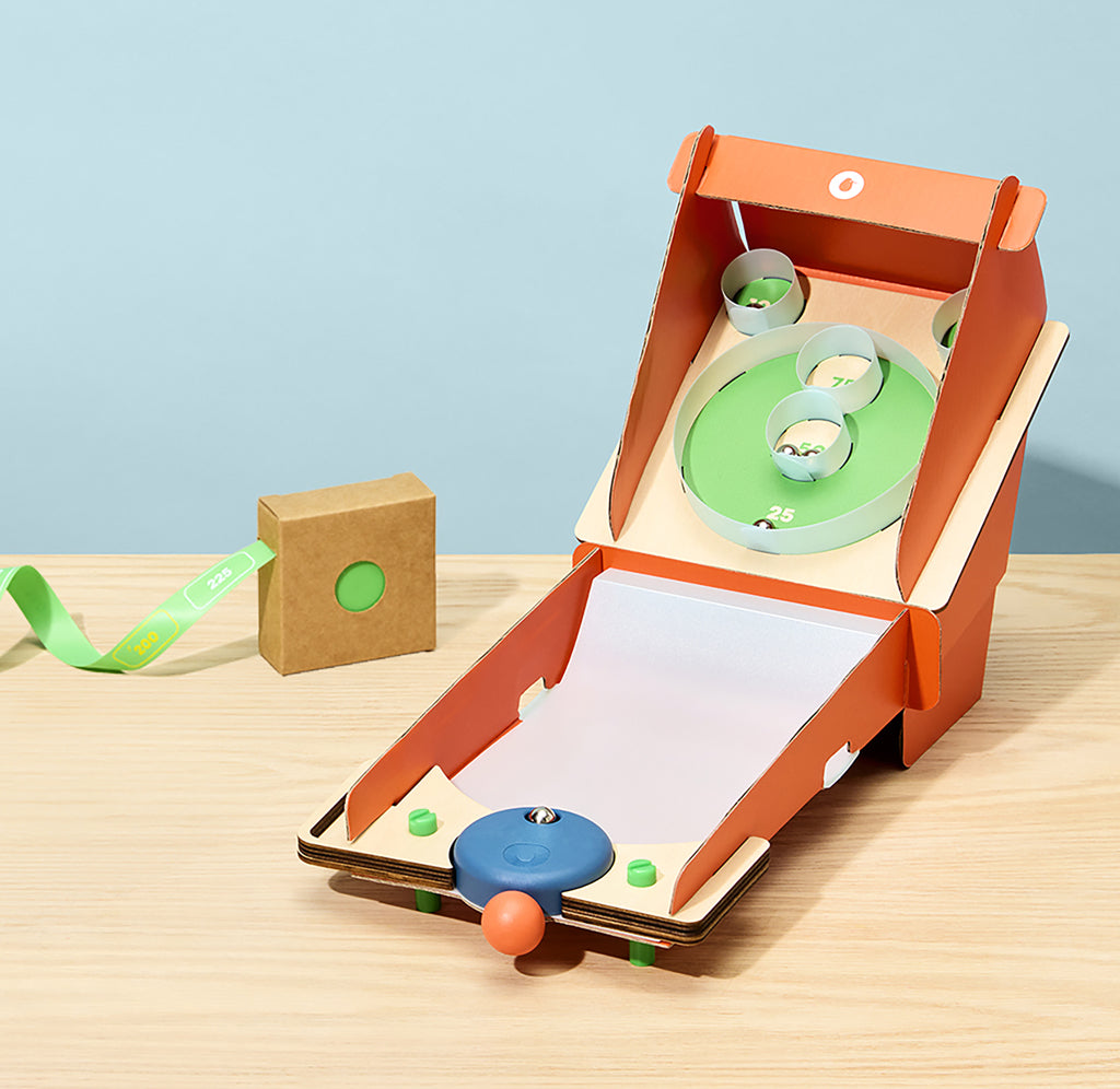 mall cardboard arcade game with colorful balls on a wooden surface and light blue background