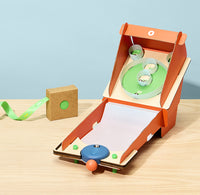 mall cardboard arcade game with colorful balls on a wooden surface and light blue background