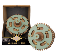 A wooden and metal Archimedes' Gear puzzle set shown with its open box and the assembled gear mechanism. The puzzle features a light green painted metal gear with bronze-colored teeth and brass pins, and a natural wood center.