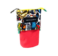 A small zippered pouch with a colorful butterfly print on the upper half and a solid red felt lower half, featuring a black label that reads 'COGNITIVE SURPLUS'.