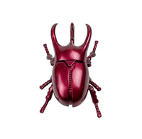 Red metallic beetle-shaped object on a white background