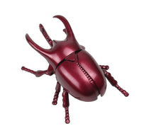 Red metallic beetle figurine on a white background