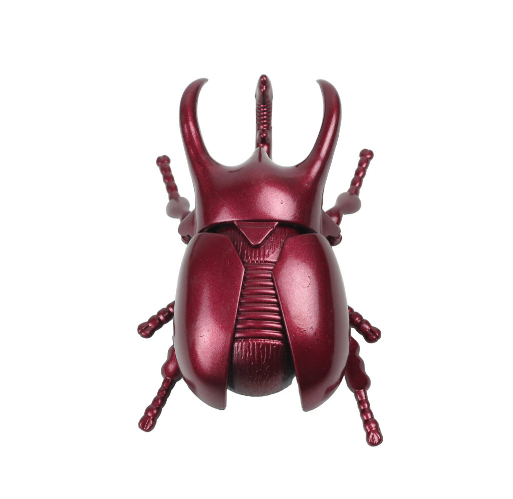 Red metallic beetle figurine on a white background