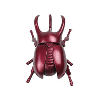 Red metallic beetle figurine on a white background