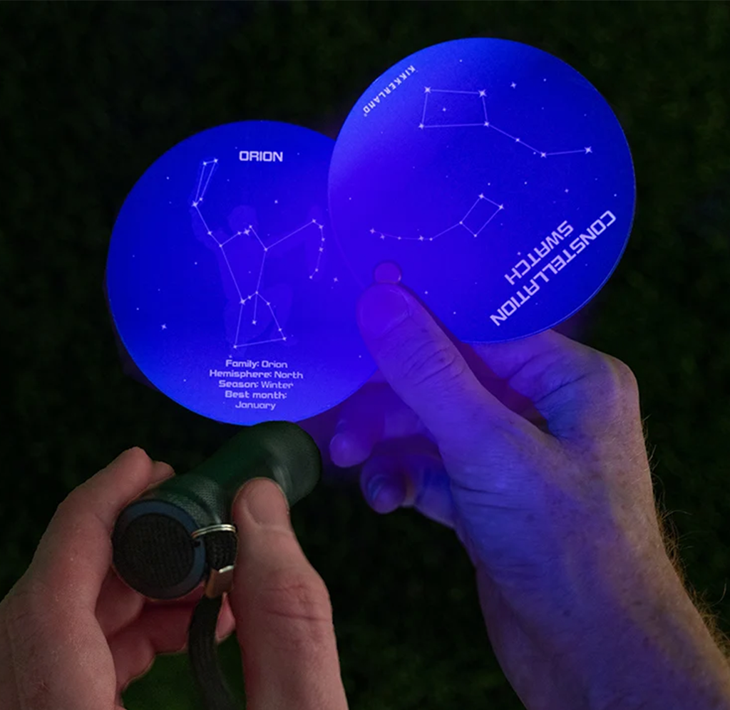 UV flashlight shining on a constellation swatchbook, illuminating a diagram of the Orion constellation.