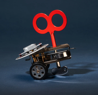 Whimsical wind-up toy vehicle with a bright red key, metal gears, wheels, and a small seat, staged against a dark blue background.
