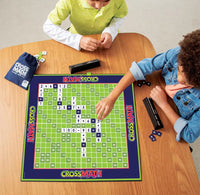 Two children playing with a CrossMath educational game on a wooden table.