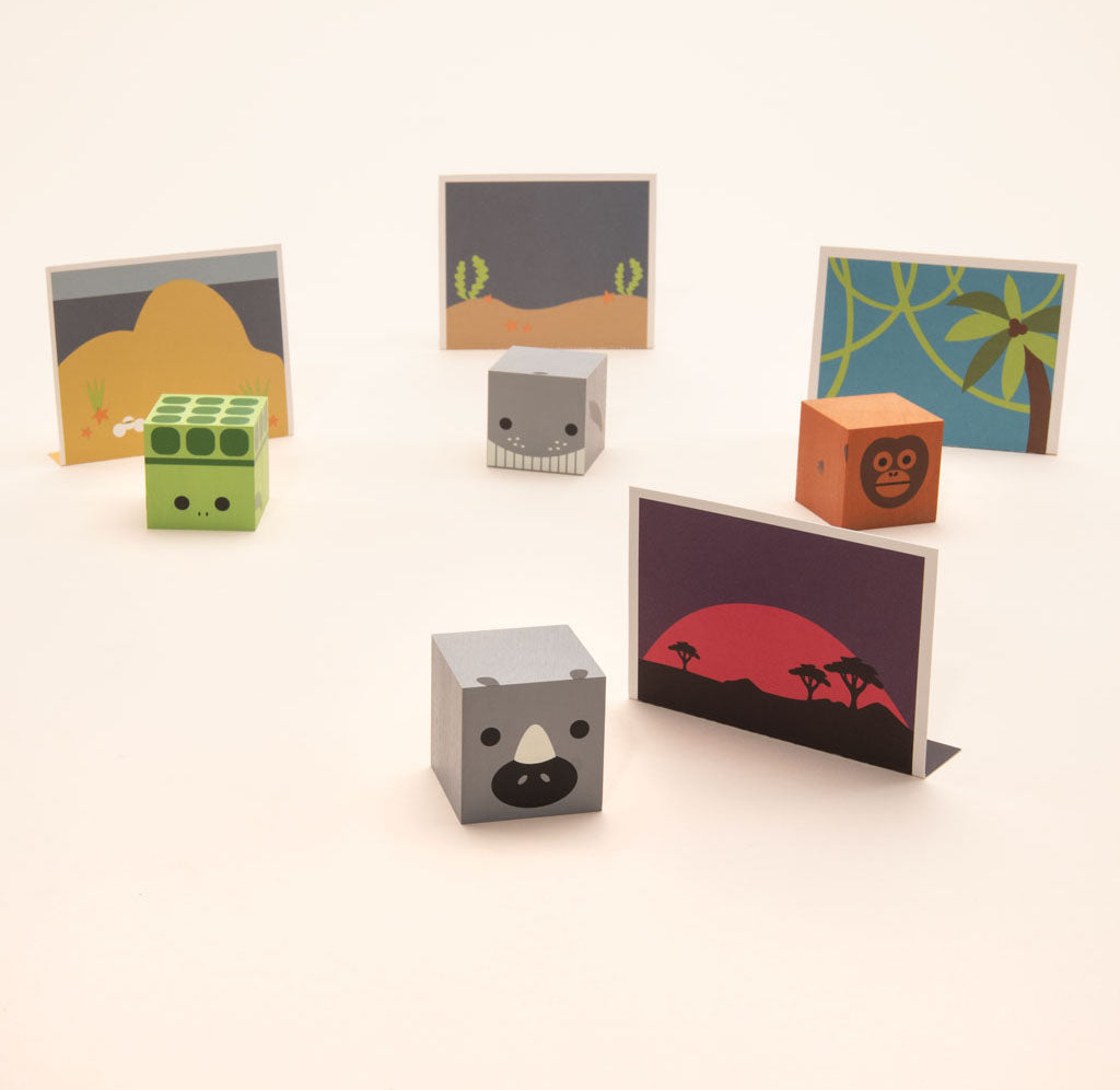 Image of four blocks: a grey humpback whale, orange orangutan, grey white rhino, and green sea turtle. There is a paper environment for each block depicting each of the animal's natural habitats.