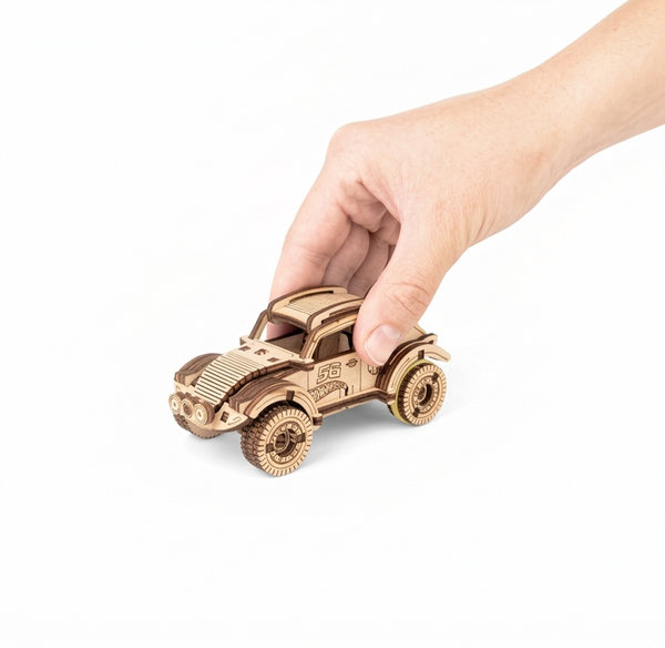 A hand gently holds a small wooden toy race car with detailed wheels and the number 56, isolated on a white background; playful, calm tone.