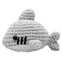 A small, grey crocheted amigurumi shark named Tank with black safety eyes, embroidered white and black gills, and a round body.