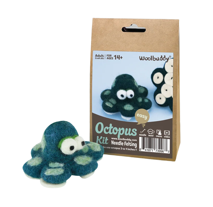 A teal felt octopus with large googly eyes sits beside a Woolbuddy beginner needle-felting kit box, suggesting a playful craft project.