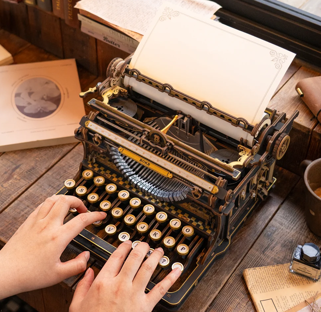 Hands typing on an ornate vintage typewriter with a blank, decorative page, surrounded by papers and ink on a wooden desk; warm, nostalgic mood.