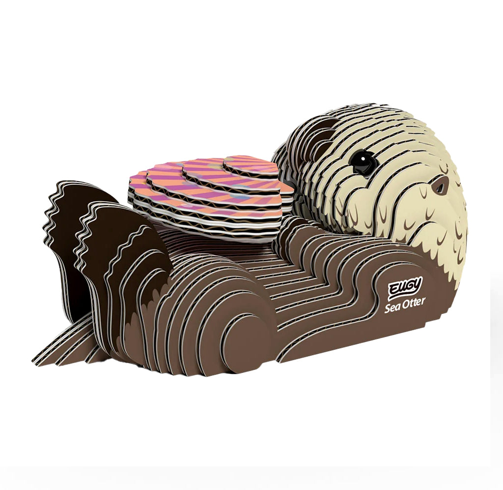 A 3D cardboard model of a sea otter, featuring a cream-colored textured head and face, dark brown paws, and a striped pink, black, and  displayed on a clean white background.
