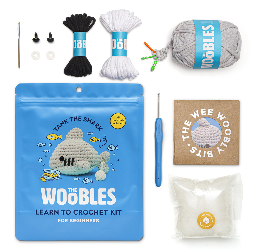 Showing everything you get in the package including a needle, plastic eyes, black, white and grey yarn instructions and stuffing.