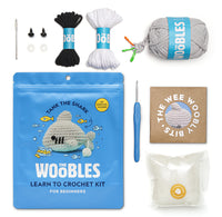 Showing everything you get in the package including a needle, plastic eyes, black, white and grey yarn instructions and stuffing.