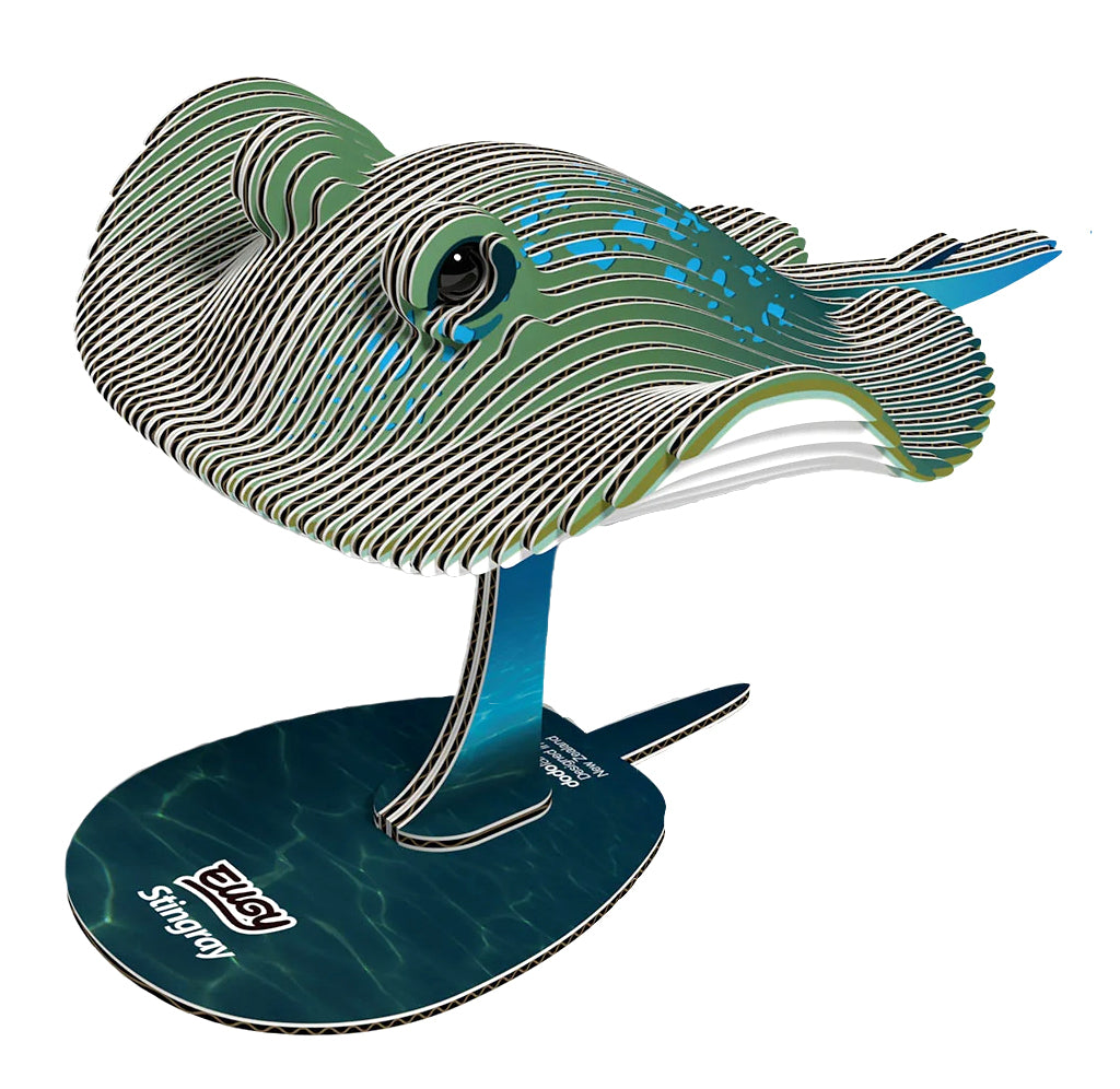 A 3D cardboard model of a stingray on a stand, featuring green, black, and white striped layers with blue accents, set against a plain white background.