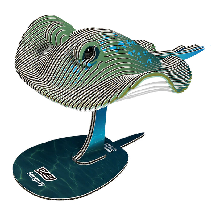 A 3D cardboard model of a stingray on a stand, featuring green, black, and white striped layers with blue accents, set against a plain white background.