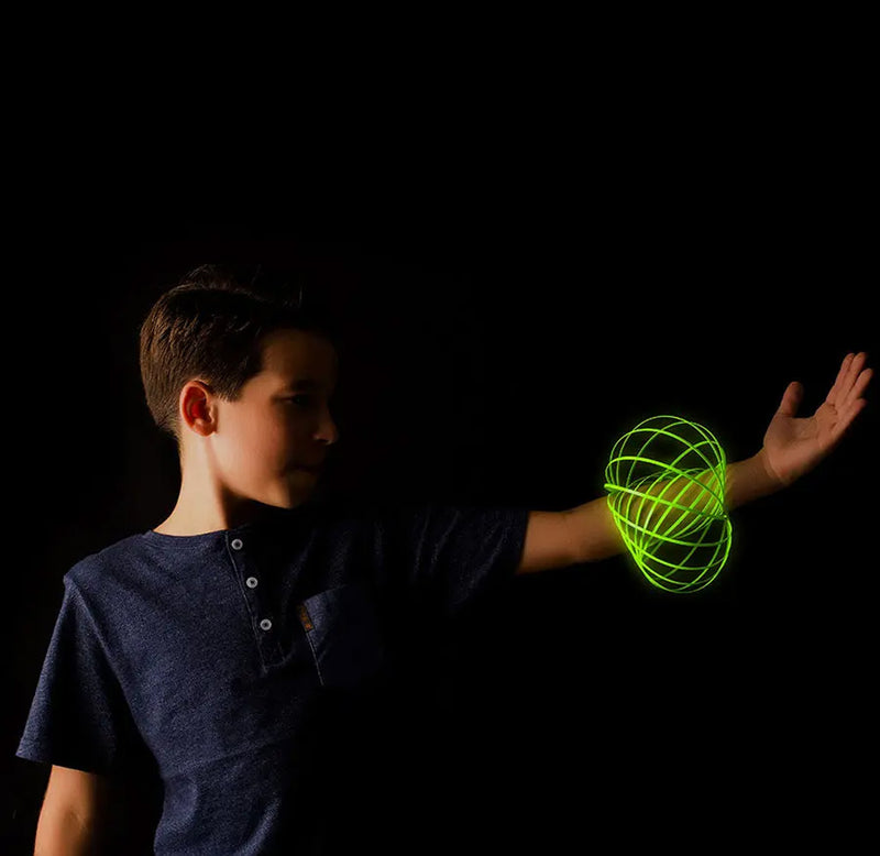 Child holding a glowing neon spring toy on their arm against a black background