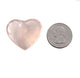 Heart-shaped pink stone next to a quarter for size comparison on a white background