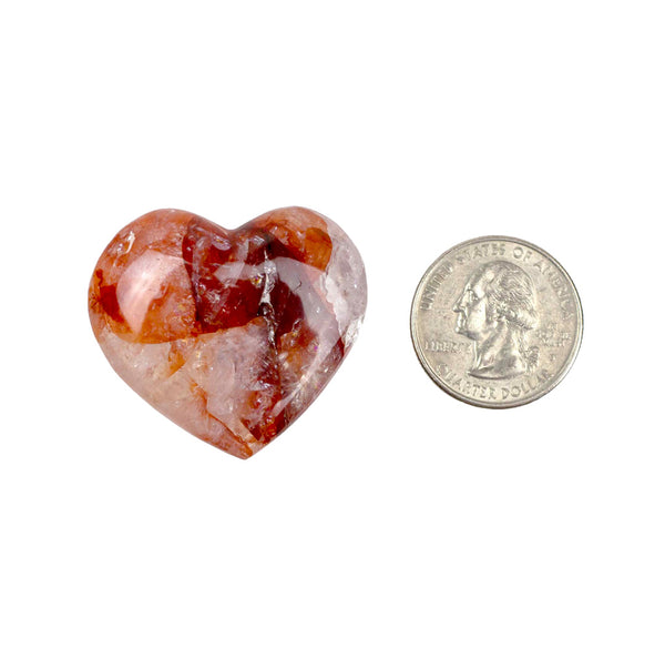 Heart-shaped stone next to a U.S. quarter dollar on a white background
