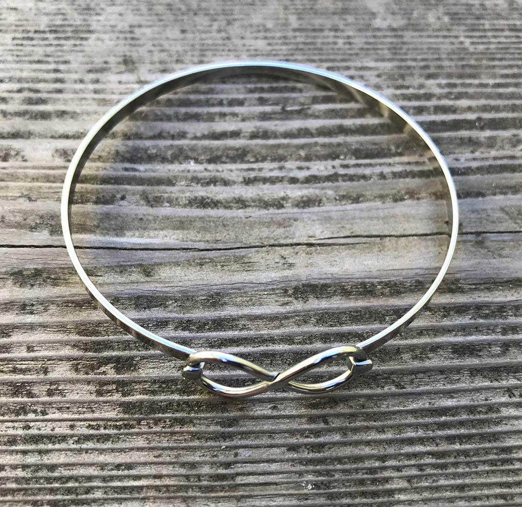 Silver infinity bracelet on a wood table. 