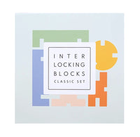 The product packaging for the 'Interlocking Blocks Classic Set' shows a white square box with a minimalist graphic of colorful interlocking puzzle-like blocks in green, blue, yellow, orange, and pink on a very light gray background.
