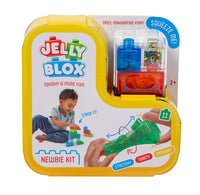 Jelly Blox Newbie Kit in its original yellow packaging, featuring a translucent green squishy toy, a blue and red squeeze dispenser, and a clear bead box, with instructional graphics and a child playing with the toy.