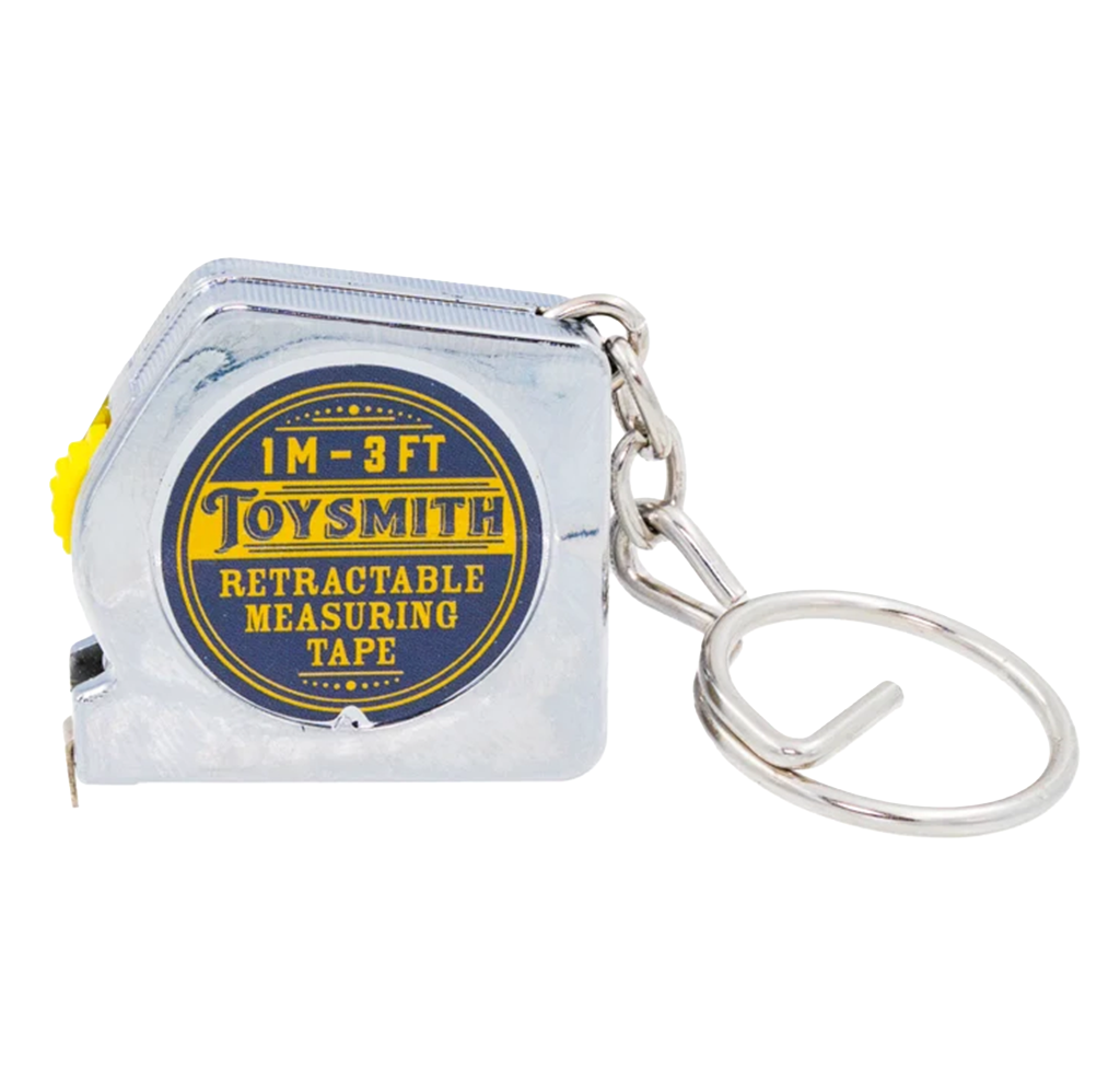 A small silver Toysmith retractable measuring tape with a blue-and-yellow label marked “1 m–3 ft,” attached to a metal key ring; practical, compact design.