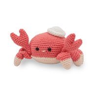A cheerful coral-red crocheted crab plush with raised claws, black bead eyes, cream-tipped legs, and a white shell-like cap, photographed on white.