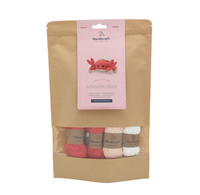 A Hardicraft crochet kit in a kraft paper pouch, with pink, coral, cream, and white yarn and a label featuring a cheerful crocheted crab.