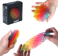 A multicolor advanced fidget toy shown with its black retail box and demonstrated by hands in three views on a white background. The toy is made of translucent grid-like plastic with rainbow color transitions.