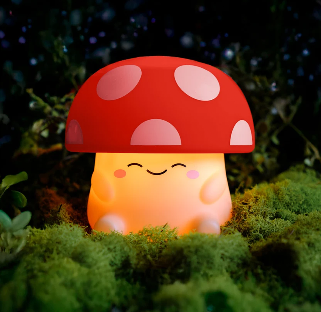 A cheerful orange mushroom character with a red, white-spotted cap glows among lush green moss in a dark forest, creating a whimsical, cozy mood.