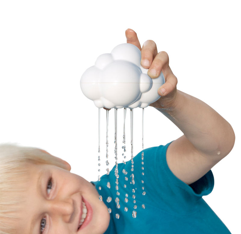 A smiling child in a blue shirt holds a white cloud-shaped toy overhead, releasing thin streams of water like rain; playful, imaginative scene on white.