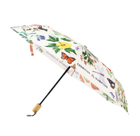 An open compact umbrella with a white background printed with colorful botanical and insect illustrations, including a butterfly, flowers, leaves, and small animals. The handle is light wood with a black grip, and the shaft is black.