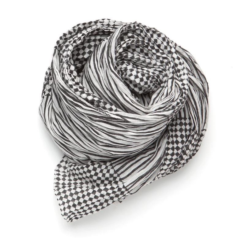 A black and white patterned scarf is rolled into a bundle.