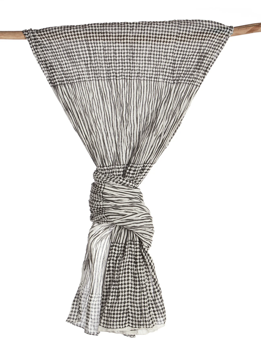 A black and white patterned scarf is draped over a wooden stick and tied near the edge. The pattern contains segments of checkers and vertical stripes. 
