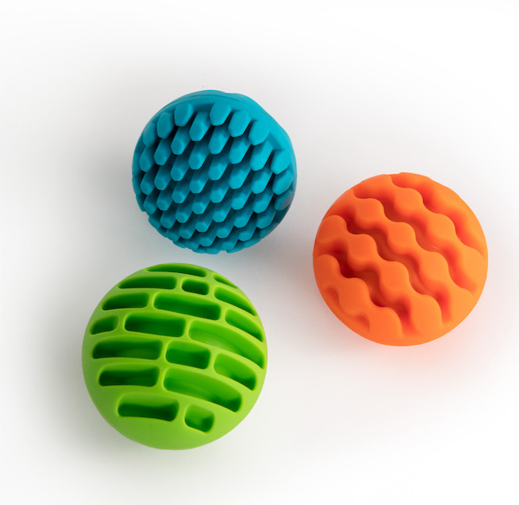 Three colorful textured spheres—teal with overlapping scales, orange with wavy ridges, and green with rounded grooves—float on a white background, creating a playful, tactile feel.