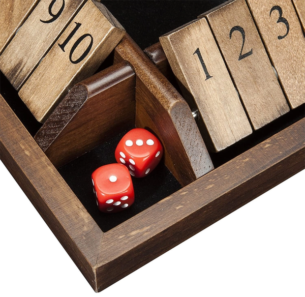 Two red dice sit in a dark wooden game box beneath numbered wooden tiles, including 9, 10, 1, 2, and 3; a warm, tactile tabletop scene.