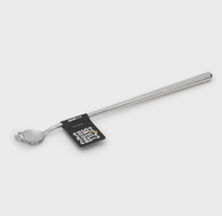 Long stainless-steel spoon with a decorative looped handle and black product tag, photographed on a plain light-gray background.