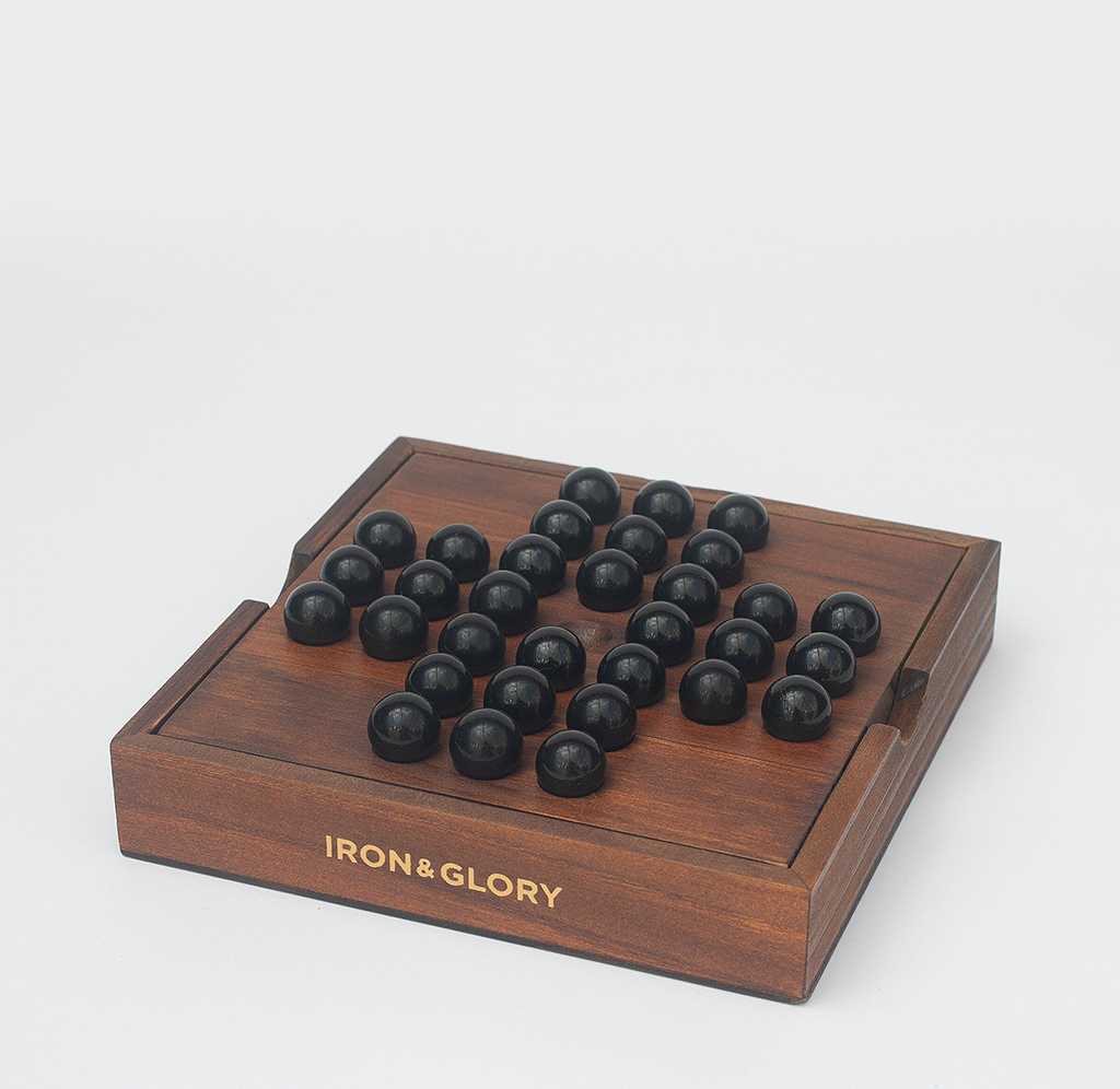 A polished wooden board holds rows of black marbles in a strategy game setup; gold “Iron & Glory” lettering adds a refined, thoughtful tone.