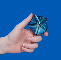A hand holding a chrome magnetic geode assembled into a pentagonal box. 