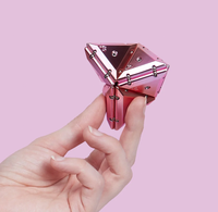 A hand holding pink chrome magnetic pieces assembled into a geode. 